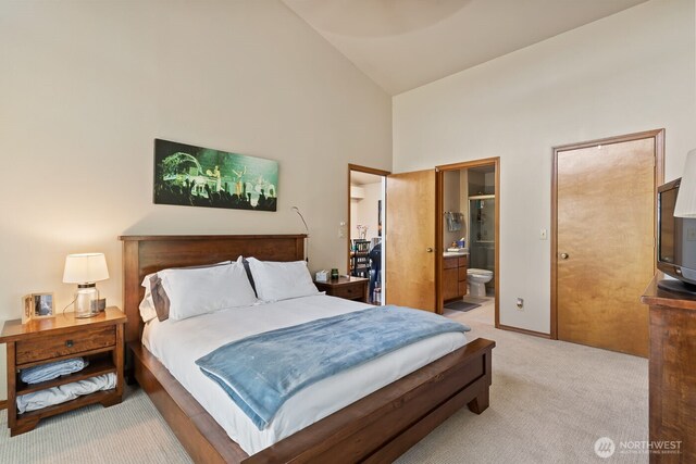 carpeted bedroom with connected bathroom and high vaulted ceiling