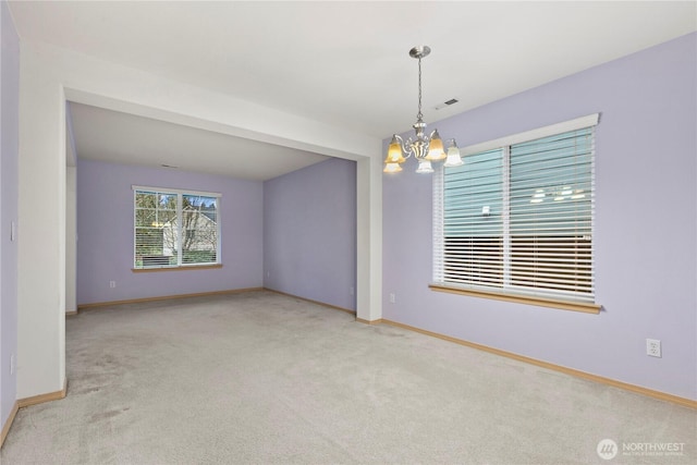 carpeted empty room with an inviting chandelier, baseboards, and visible vents