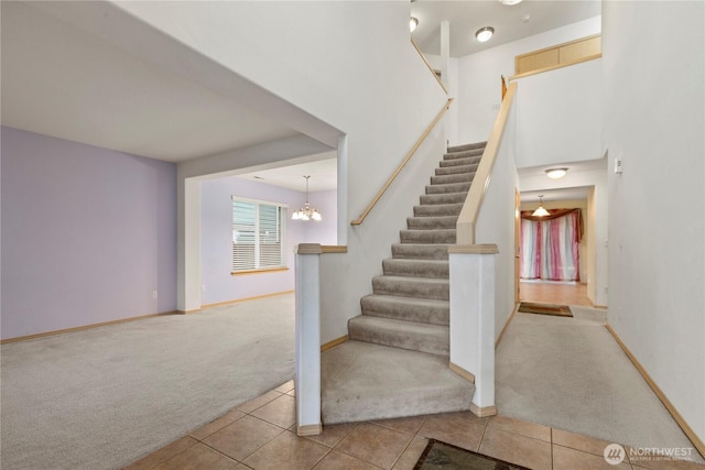 staircase featuring tile patterned floors, a notable chandelier, baseboards, and carpet