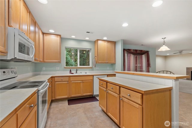 kitchen with visible vents, a sink, a center island, white appliances, and light countertops