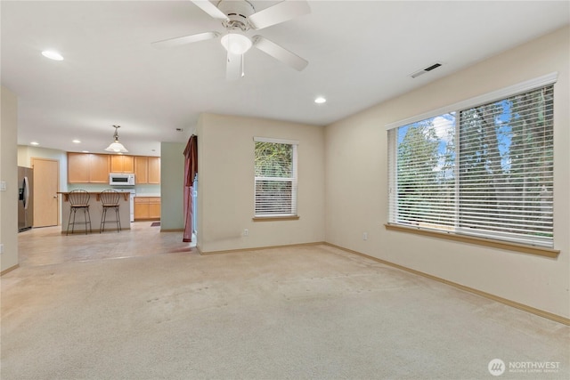 unfurnished living room with recessed lighting, baseboards, light colored carpet, and a healthy amount of sunlight