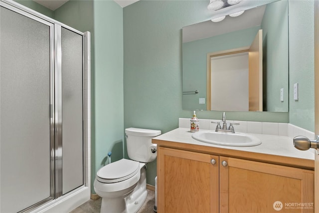 bathroom featuring toilet, a stall shower, and vanity