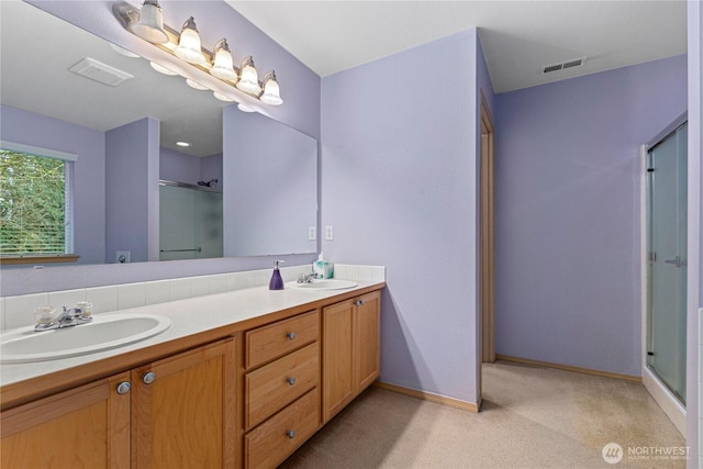 full bathroom with double vanity, a stall shower, visible vents, and a sink