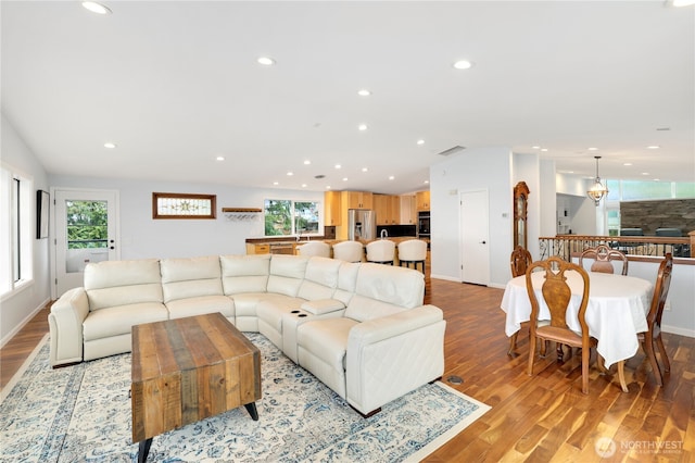 living area featuring a healthy amount of sunlight, light wood-style floors, and lofted ceiling