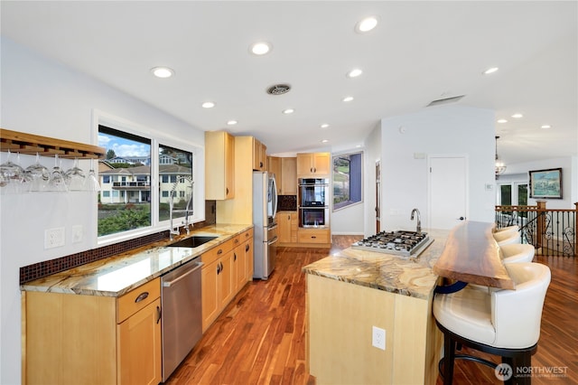 kitchen featuring a breakfast bar area, visible vents, appliances with stainless steel finishes, and light brown cabinetry