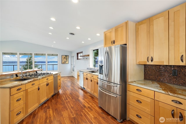 kitchen featuring visible vents, light brown cabinets, vaulted ceiling, decorative backsplash, and stainless steel appliances