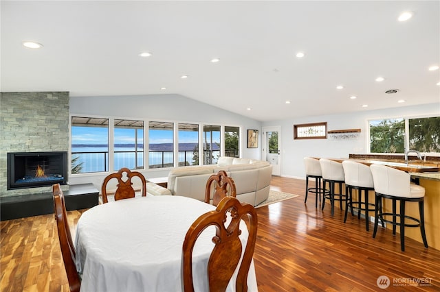 dining area with recessed lighting, a fireplace, wood finished floors, and vaulted ceiling