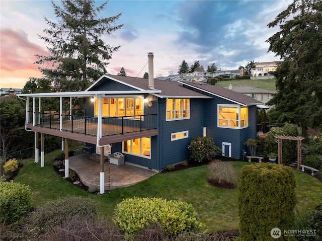 back of house featuring a deck, a patio, a lawn, and a shingled roof