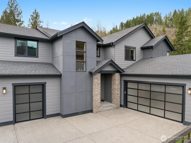 view of front of property featuring driveway, a shingled roof, and an attached garage