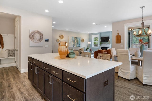 kitchen with a chandelier, open floor plan, dark brown cabinets, and wood finished floors