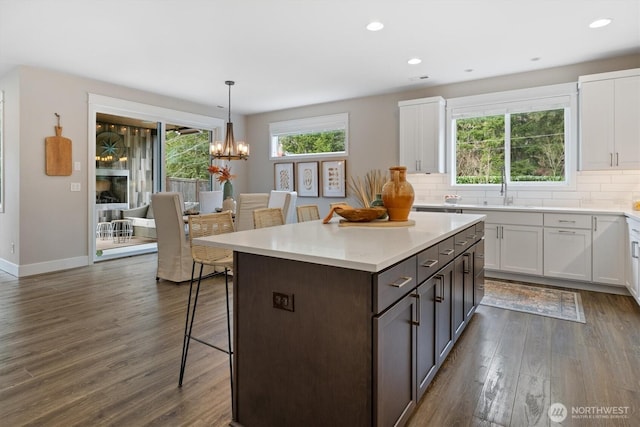 kitchen with a breakfast bar, decorative backsplash, dark wood finished floors, and white cabinetry