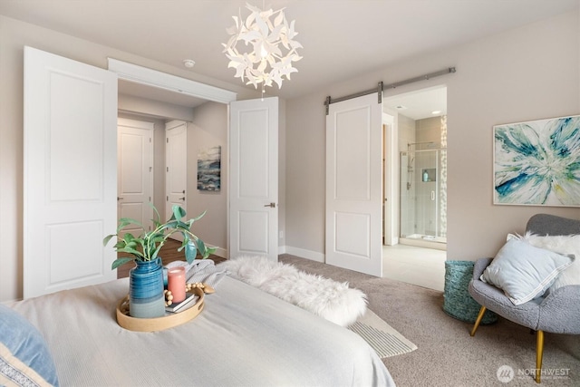 carpeted bedroom with baseboards, ensuite bathroom, and a barn door