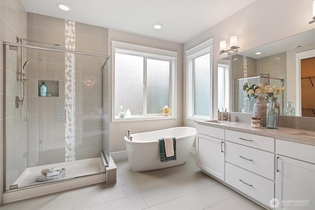 full bath featuring double vanity, a shower stall, a freestanding bath, and a sink