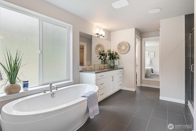 bathroom featuring tile patterned floors, a freestanding tub, a shower stall, baseboards, and vanity