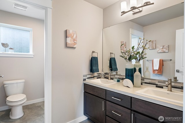 full bath featuring double vanity, visible vents, toilet, and a sink