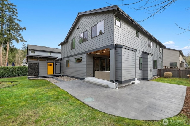 back of house featuring fence, a lawn, and a patio area