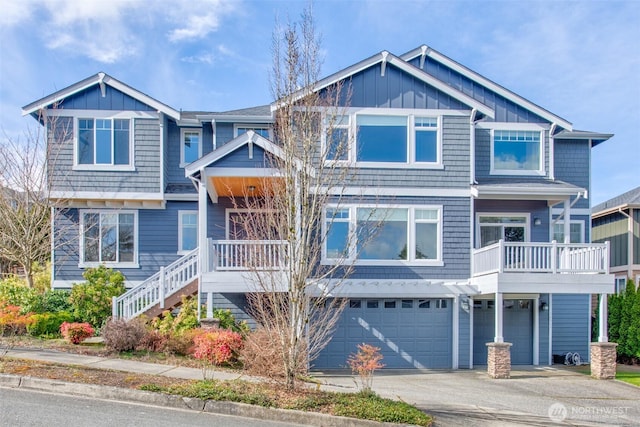 view of front of house with board and batten siding, an attached garage, stairs, and driveway