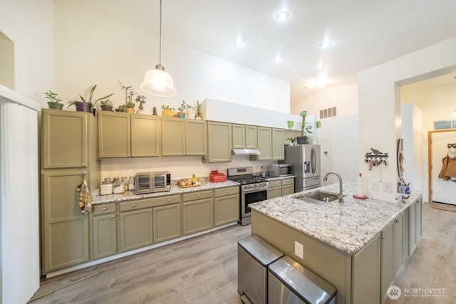 kitchen featuring light wood finished floors, under cabinet range hood, appliances with stainless steel finishes, high vaulted ceiling, and a sink