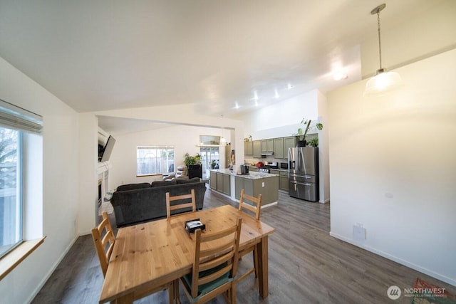 dining room with a fireplace, baseboards, dark wood-type flooring, and lofted ceiling