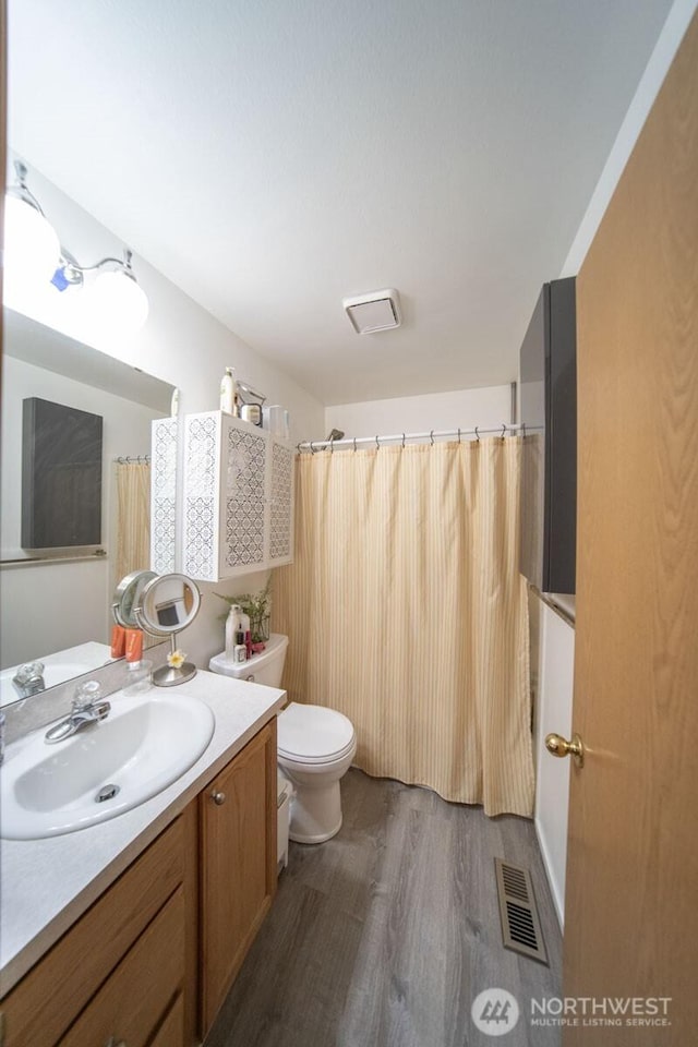 full bathroom featuring vanity, toilet, wood finished floors, and visible vents