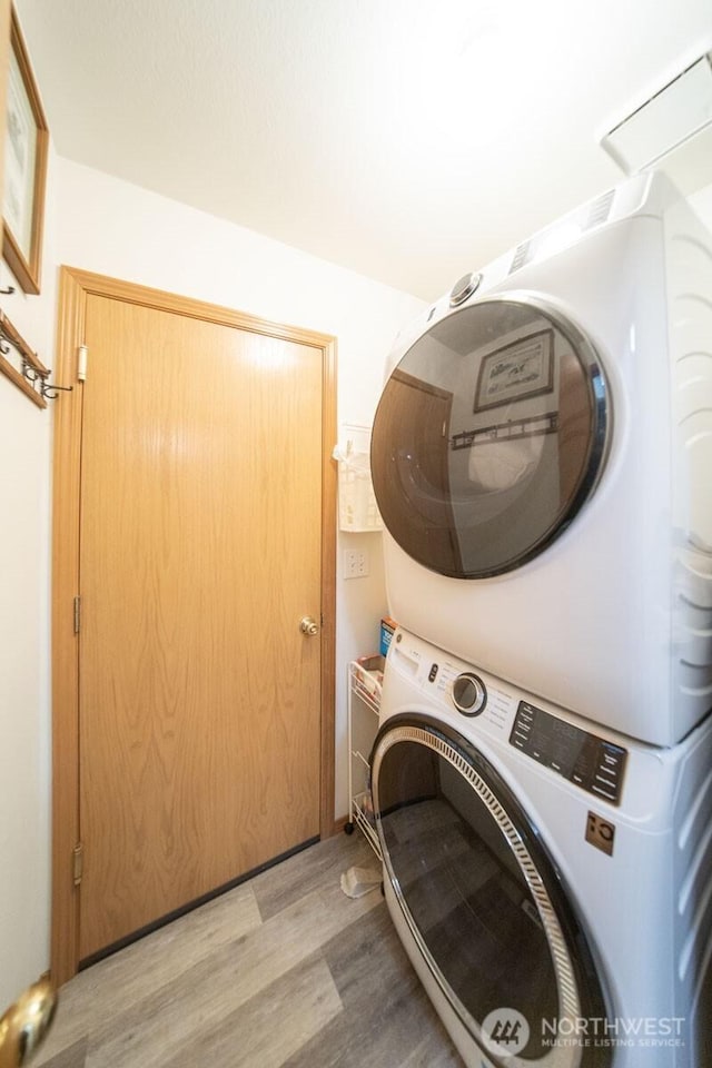 washroom with laundry area, light wood-style flooring, and stacked washer / drying machine