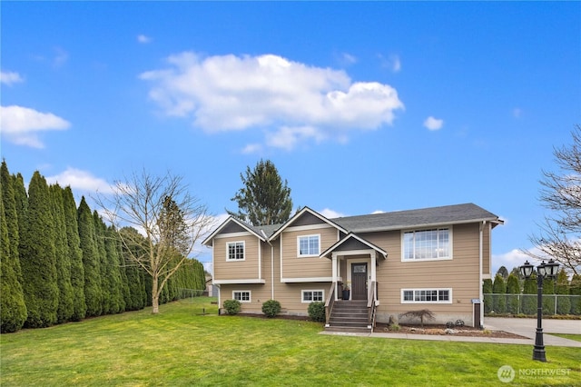 raised ranch featuring a front yard and fence