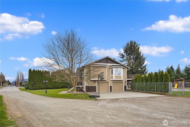 view of front of property with driveway, an attached garage, a front lawn, and fence