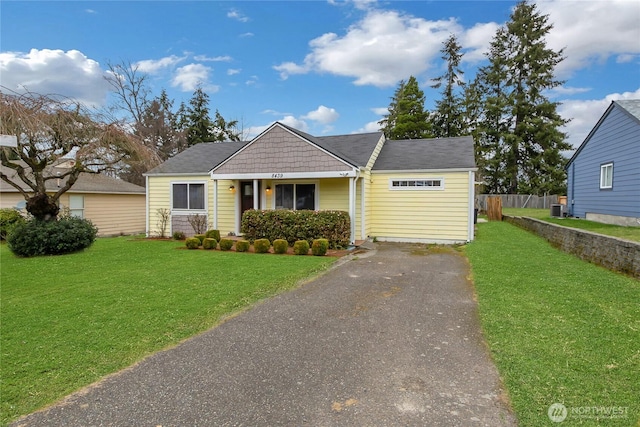 view of front of home with cooling unit, driveway, a front yard, and fence