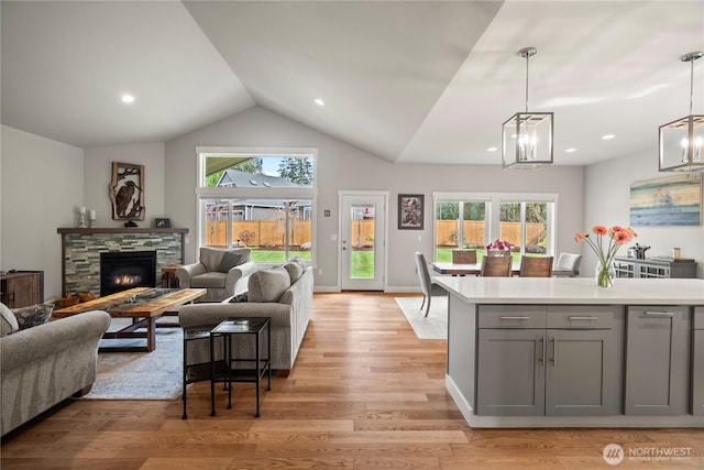 living area with light wood finished floors, plenty of natural light, a fireplace, and vaulted ceiling