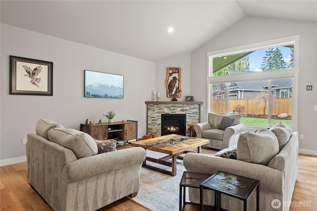 living area with a fireplace, light wood-style floors, baseboards, and high vaulted ceiling