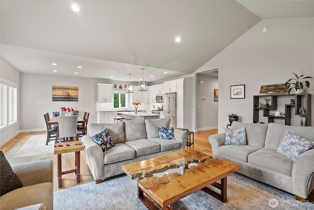 living room with recessed lighting, baseboards, light wood finished floors, and high vaulted ceiling