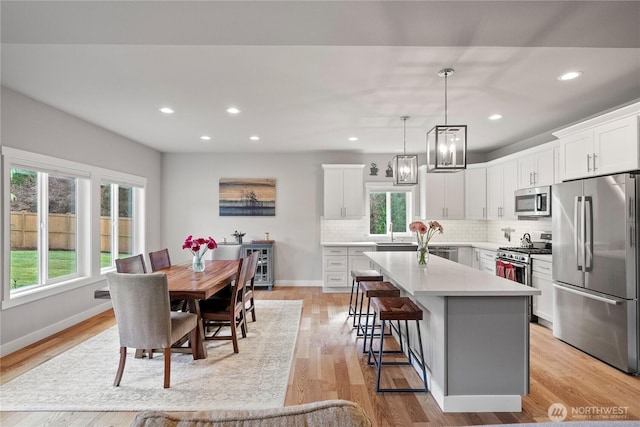 kitchen with backsplash, a kitchen island, a wealth of natural light, appliances with stainless steel finishes, and a kitchen breakfast bar