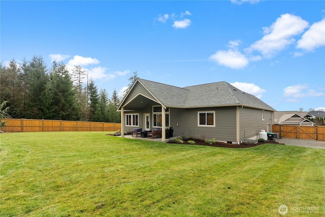 rear view of property featuring a lawn, a patio, a fenced backyard, a shingled roof, and an outdoor hangout area