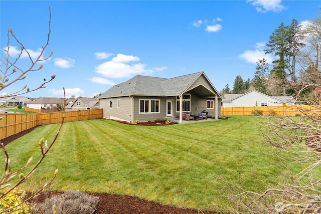 rear view of property with a patio area, a yard, and a fenced backyard