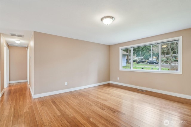 unfurnished room featuring light wood-style flooring, baseboards, and visible vents