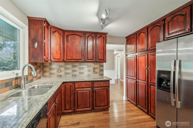 kitchen with backsplash, stainless steel fridge with ice dispenser, light stone counters, light wood-style flooring, and a sink