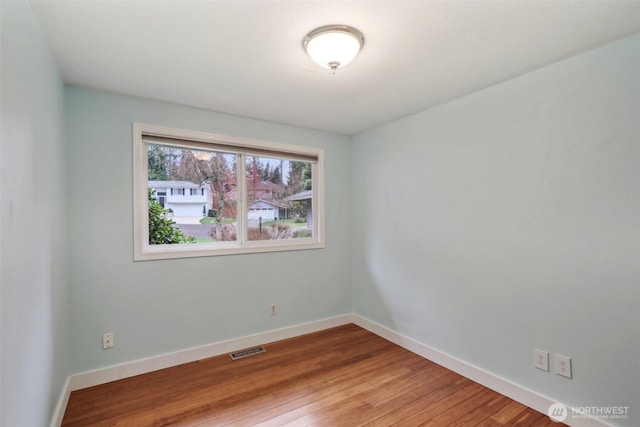 unfurnished room with wood finished floors, visible vents, and baseboards