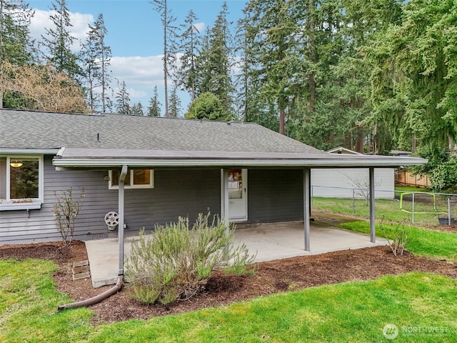 view of front of property featuring a carport, roof with shingles, a front lawn, and fence