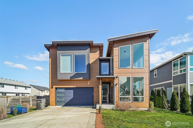 contemporary house featuring a front lawn, fence, stucco siding, a garage, and driveway