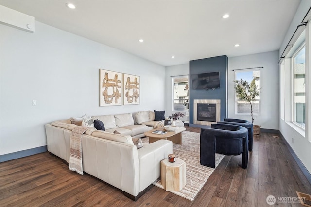 living area with a large fireplace, recessed lighting, dark wood-type flooring, and baseboards