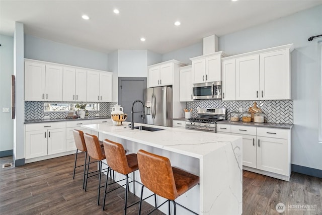 kitchen with a sink, a kitchen island with sink, white cabinetry, and stainless steel appliances