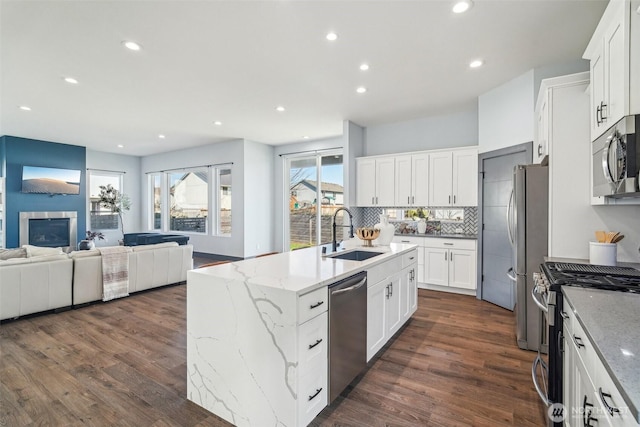 kitchen with a kitchen island with sink, a sink, open floor plan, dark wood-style floors, and stainless steel appliances