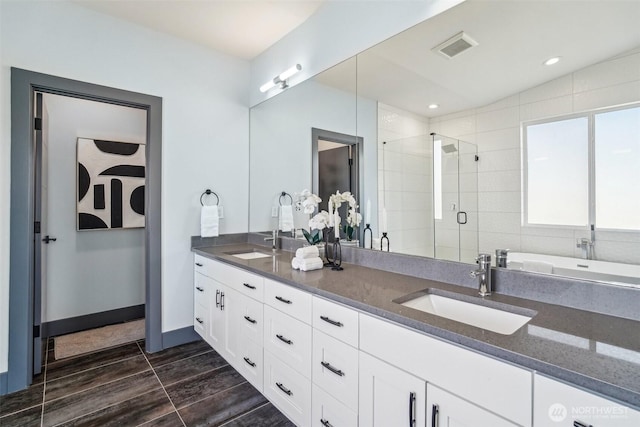 bathroom featuring double vanity, visible vents, a shower stall, and a sink