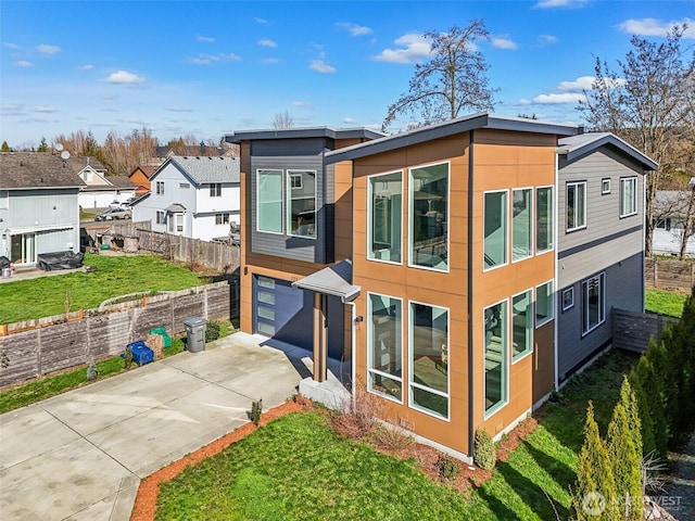 rear view of property featuring a residential view, driveway, a garage, and fence