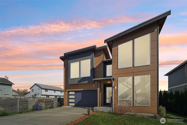 modern home with concrete driveway, a garage, and fence