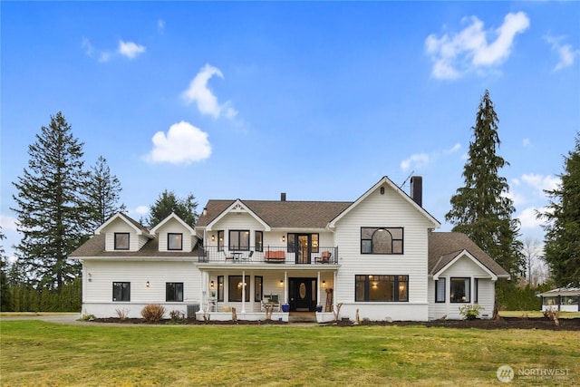 modern farmhouse style home featuring a front lawn, a balcony, covered porch, and a shingled roof