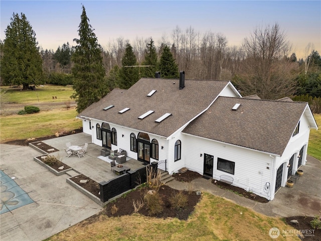 exterior space with driveway, a patio, french doors, roof with shingles, and a chimney