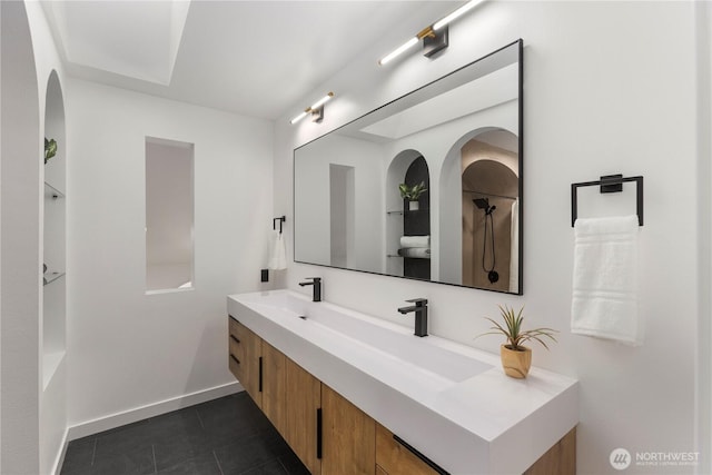 full bath featuring double vanity, baseboards, a sink, and tile patterned flooring