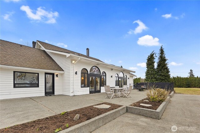 rear view of property with a patio area, fence, french doors, and roof with shingles