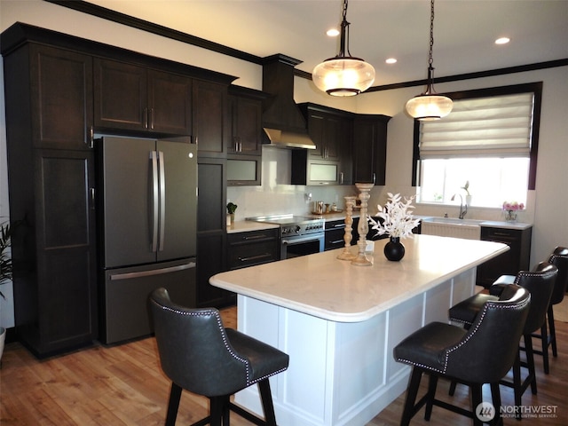 kitchen with custom exhaust hood, a kitchen breakfast bar, stainless steel appliances, and a sink